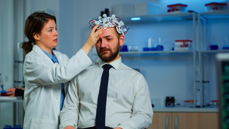 Neurologist doctor analysing brain of man and nervous system using brainwave scanning headset. Researcher using high tech developing neurological innovation monitoring side effects on monitor screen